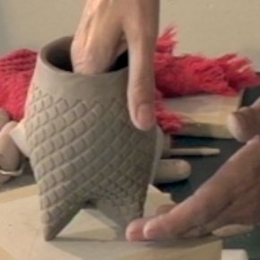 An someone's hands building a textured cup with a darted bottom