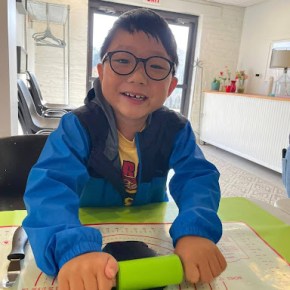a boy with a green rolling pin rolling out black fondant