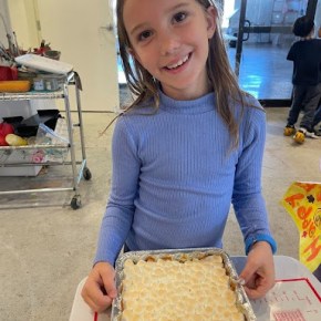Girl in blue shirt standing with a marshmallow covered sweet potato casserole